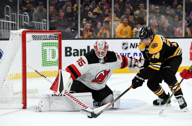 Jake DeBrusk of the Boston Bruins and Cory Schneider of the New Jersey Devils